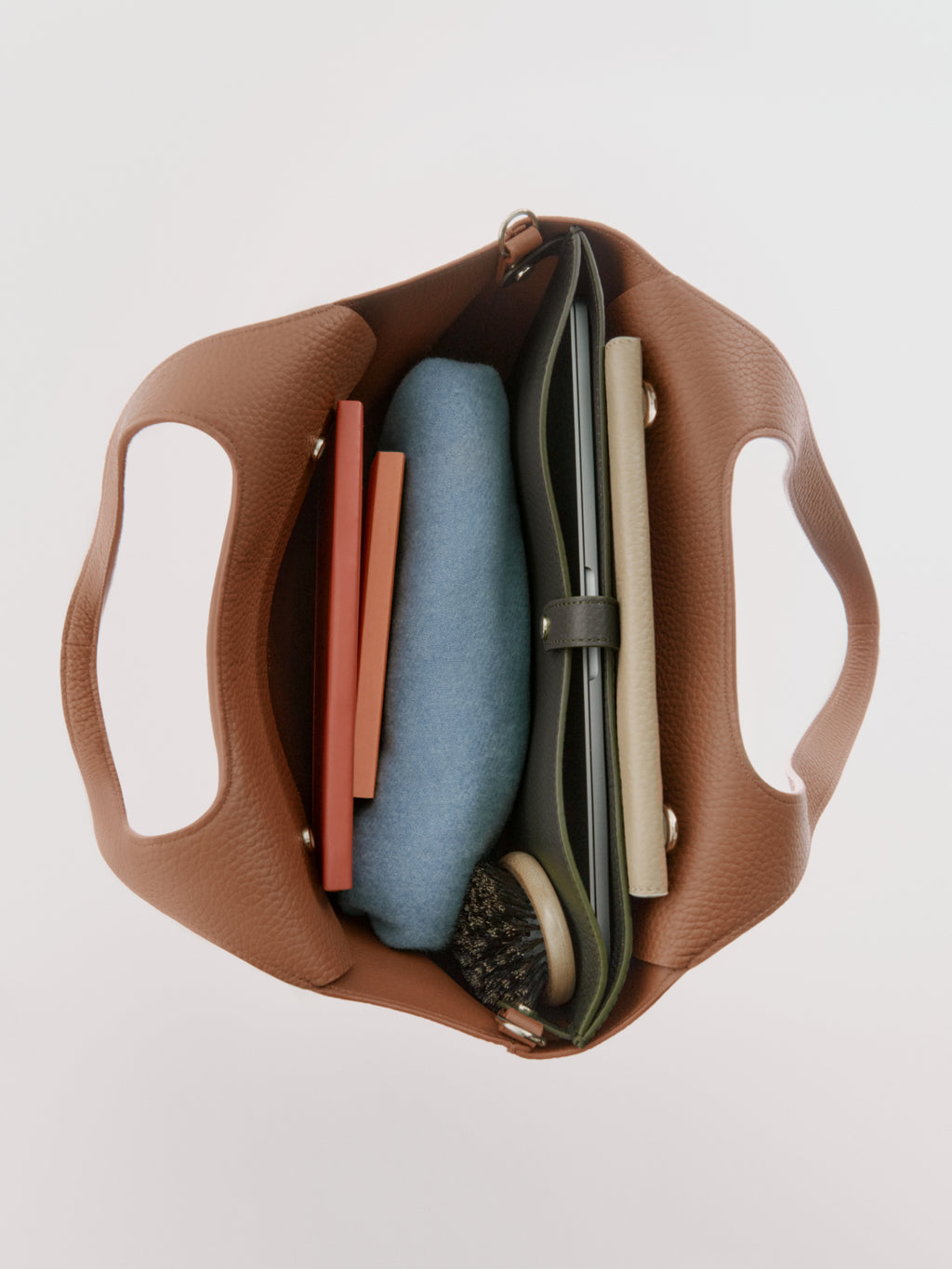 Top view of an open bag with books and a brush inside.