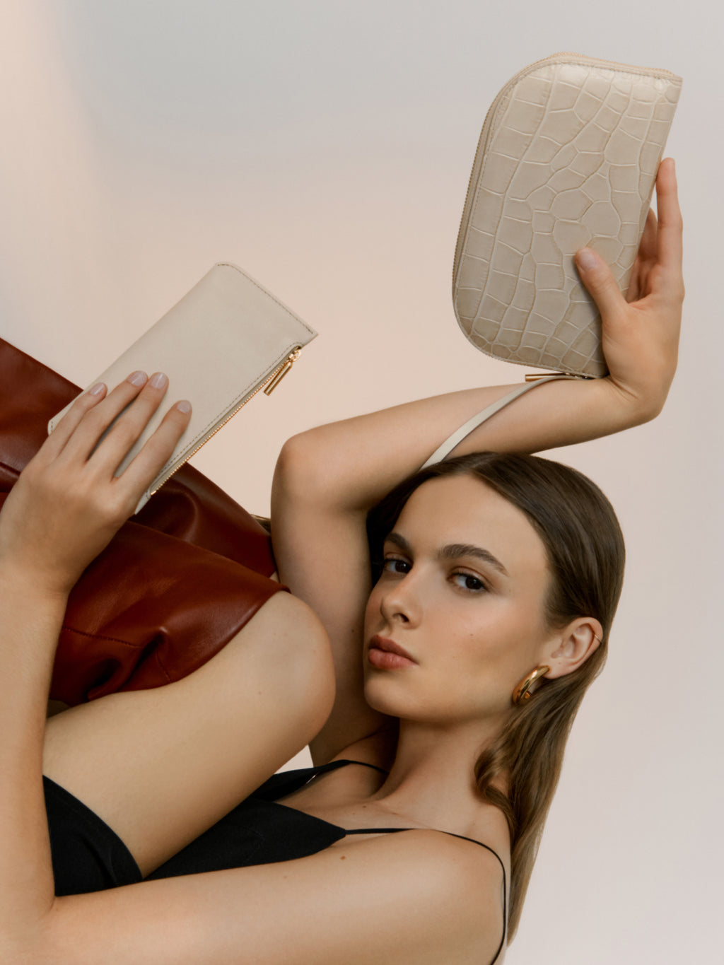 Woman posing with two clutches, one held above her head