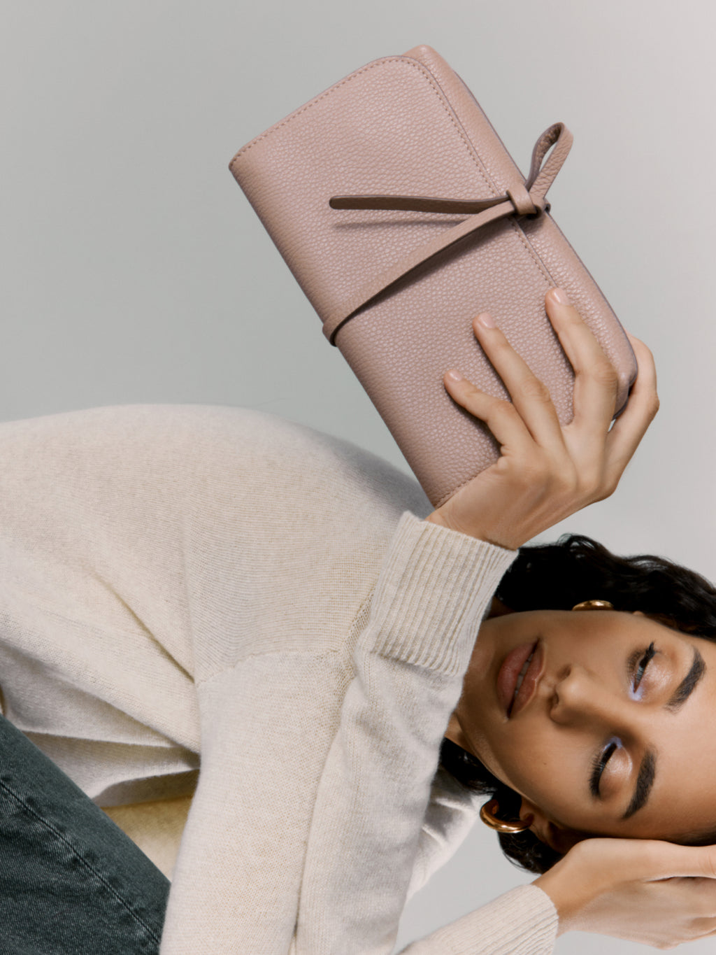 Woman holding a wallet above her head while reclining.