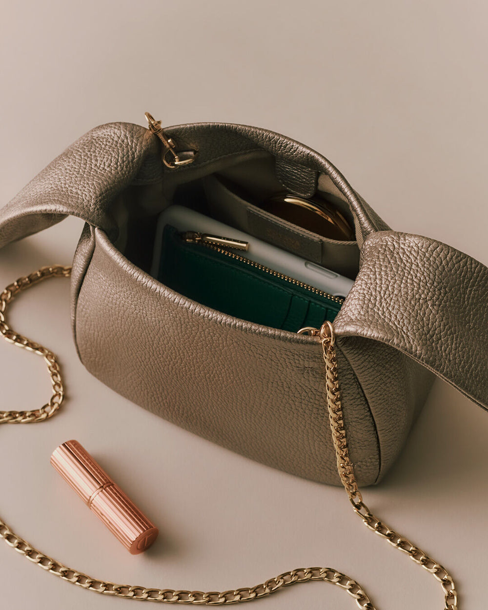 Open handbag with visible contents and a lipstick beside it.