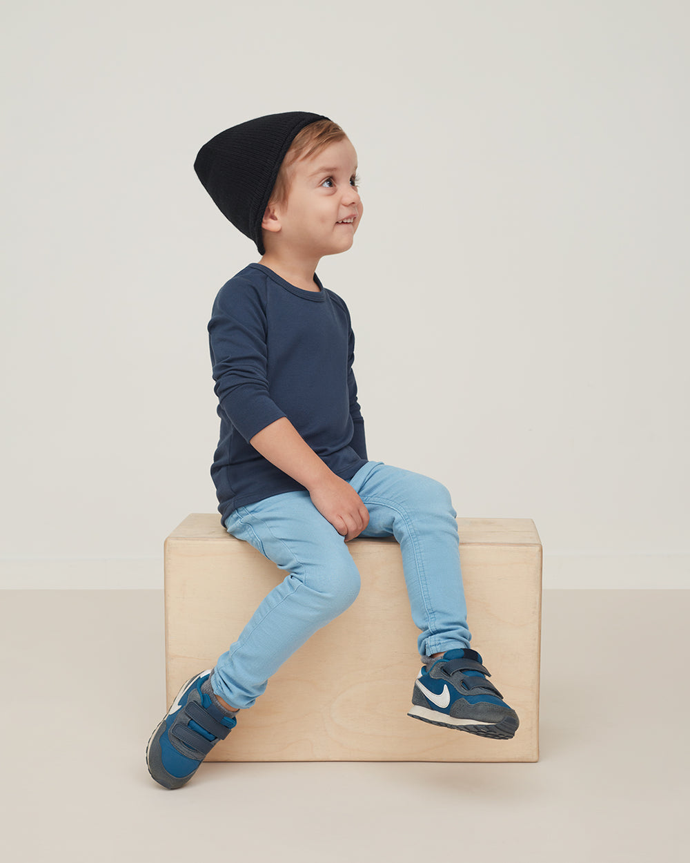 Child sitting on a wooden box, looking to the side