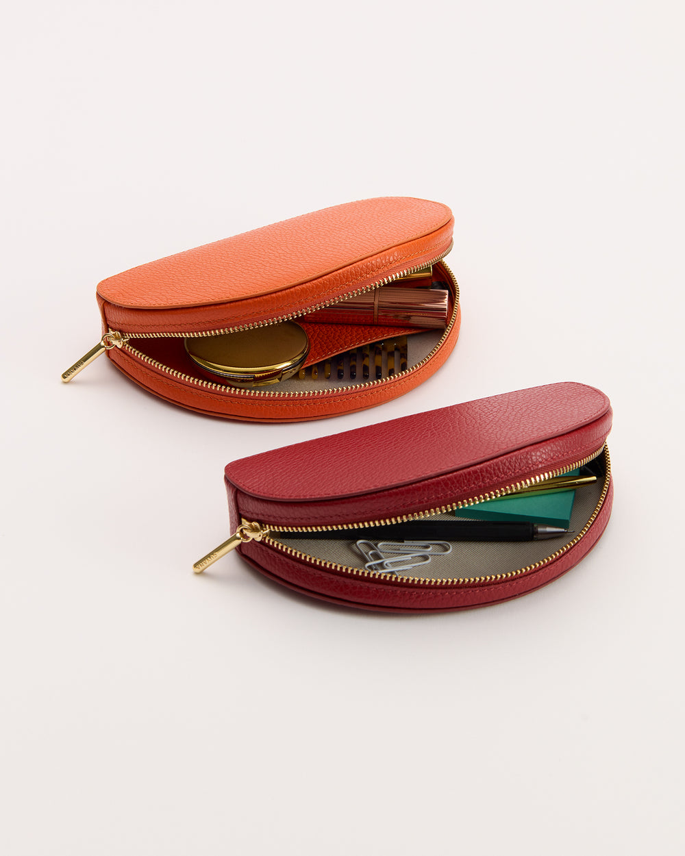 Two oval-shaped pouches with zippers, containing various small items.