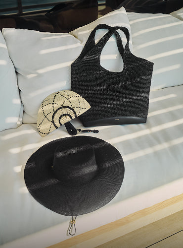 Tote bag, round fan, and wide-brimmed hat on a cushioned seat.