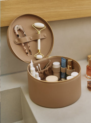 Round organizer with skincare items and tools on a bathroom counter.