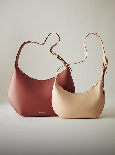 Two handbags with curved straps displayed together.