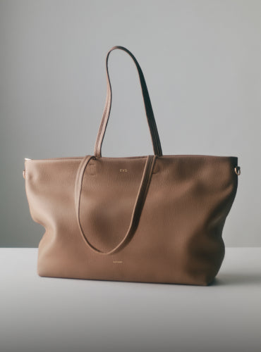 Large tote bag with thin straps on a surface.