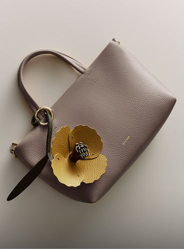 Handbag with a flower keychain attached.