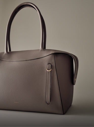 Handbag with two handles on a plain background.