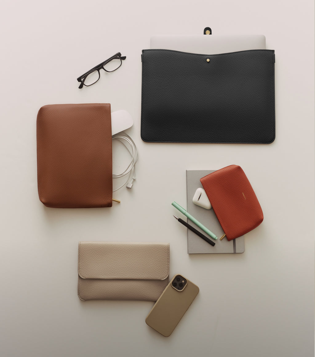 Glasses, pouches, phone, and pens arranged on a surface.