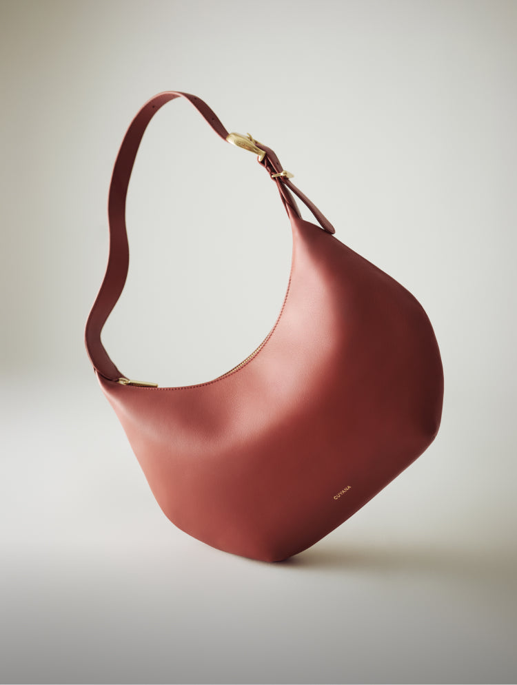 A sleek leather handbag with a curved design and a shoulder strap.