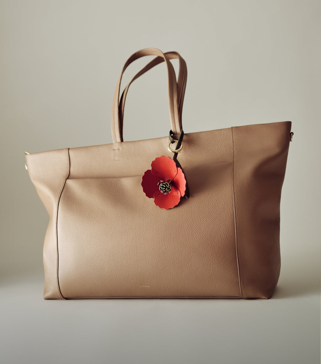 Large tote bag with handles and flower charm accessory.