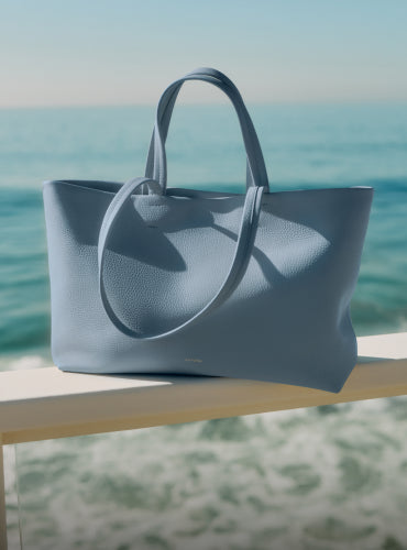 Tote bag on a ledge with ocean in the background.