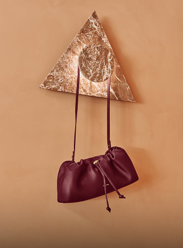 Leather travel bag hanging on a marble and triangle wall design.