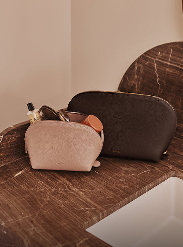 A set of two beauty cases sitting on a marbled countertop.