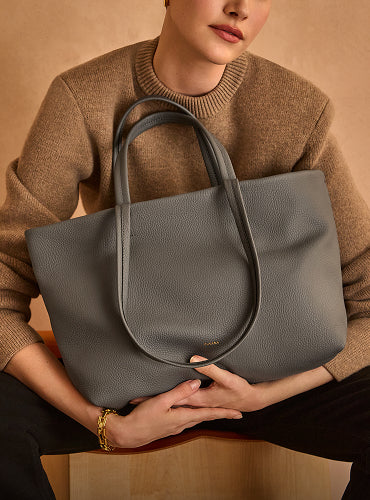 Person holding a large tote bag while sitting.