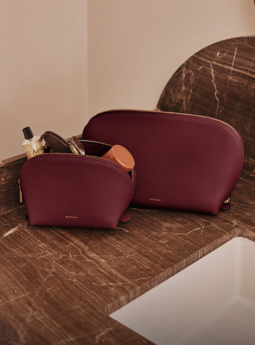 Two zippered pouches on a marble counter with toiletries inside.