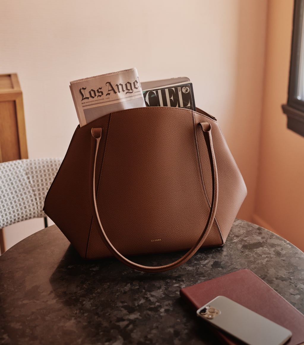 Handbag on table with magazines and phone nearby