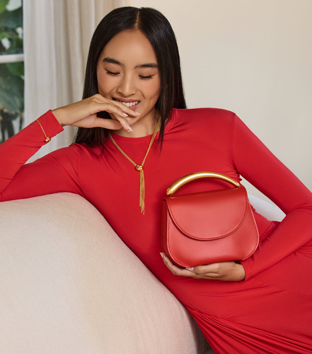 Person in a red dress holding a handbag with a gold handle.