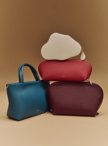 Four textured handbags stacked in a pyramid shape.