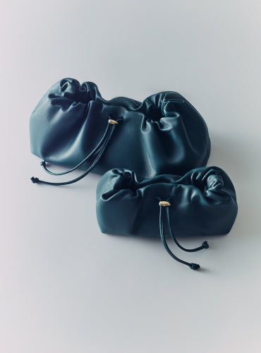 Two drawstring pouches with ruched detailing placed side by side.