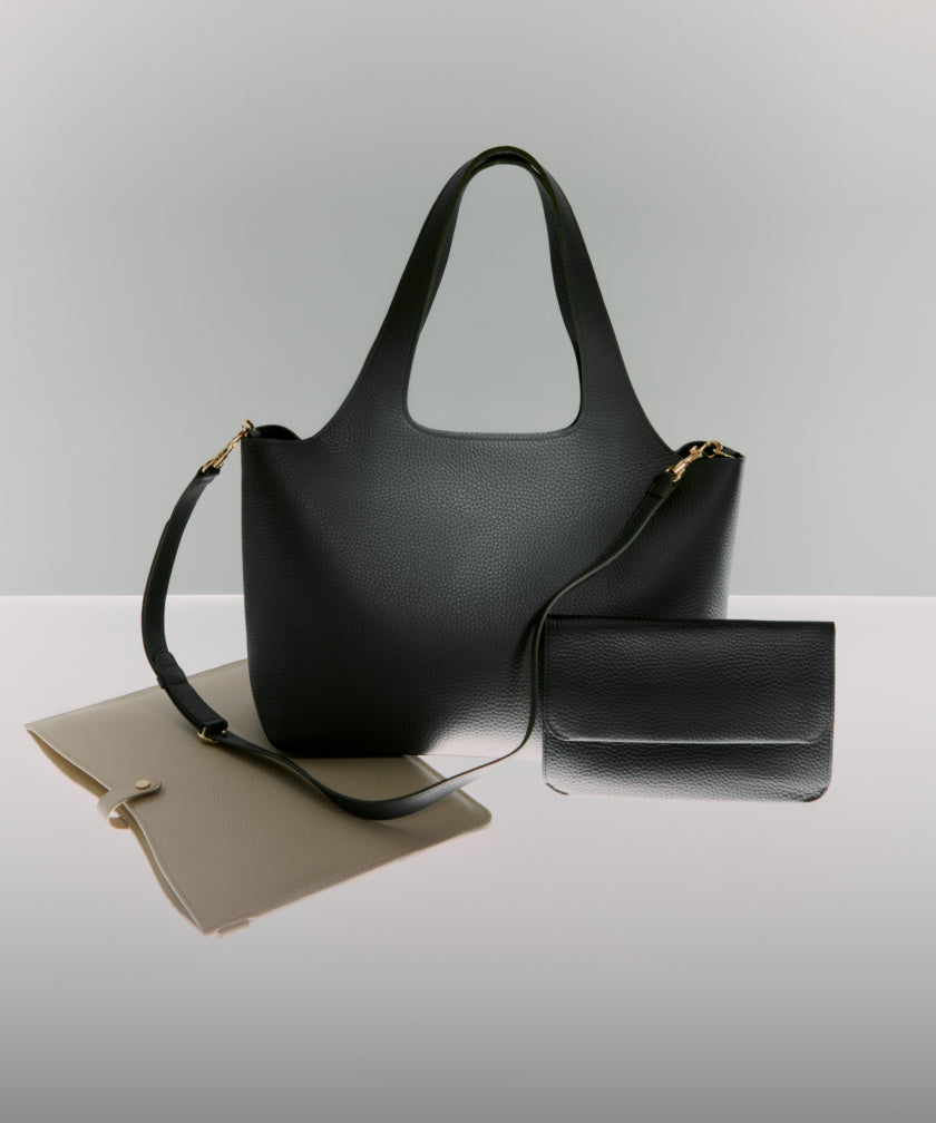 Linked Image: Directs to Work Bags shop page (https://cuyana.com/collections/work-bags). Image Description: The Cuyana System Laptop Sleeve in color stone (left), the  System Tote (center) and Flap Bag (right) in color Dark Olive
