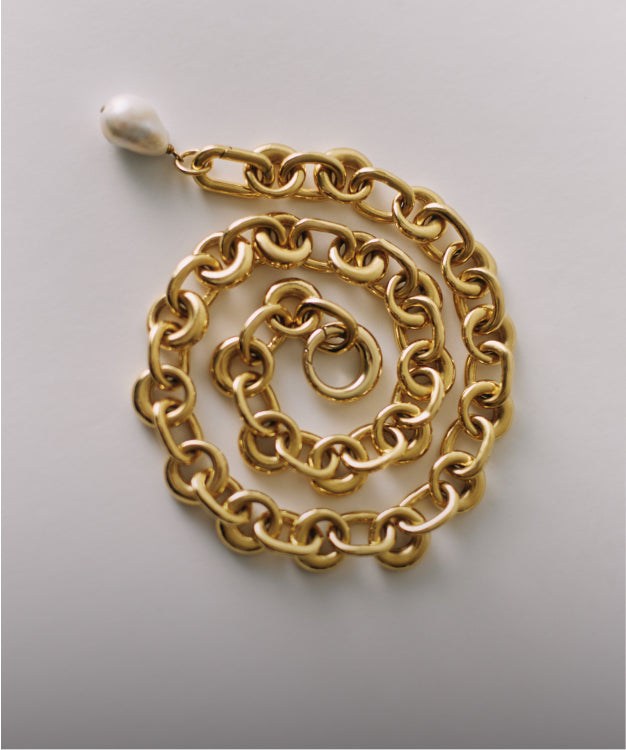 Chain necklace curled in a spiral shape with a single hanging pearl.