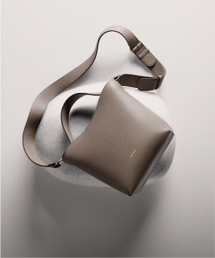 Crossbody bag with wide strap on rounded surface