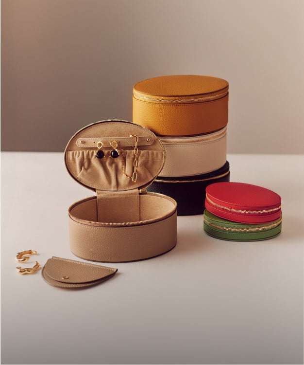 Stacked circular boxes and small open case with earrings on a table.