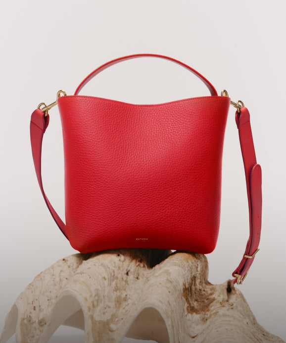 Linked Image: Directs to Mini Totes and Crossbody Bags shop page. Image Description: Cuyana Linea bucket bag in Lipstick (red). 