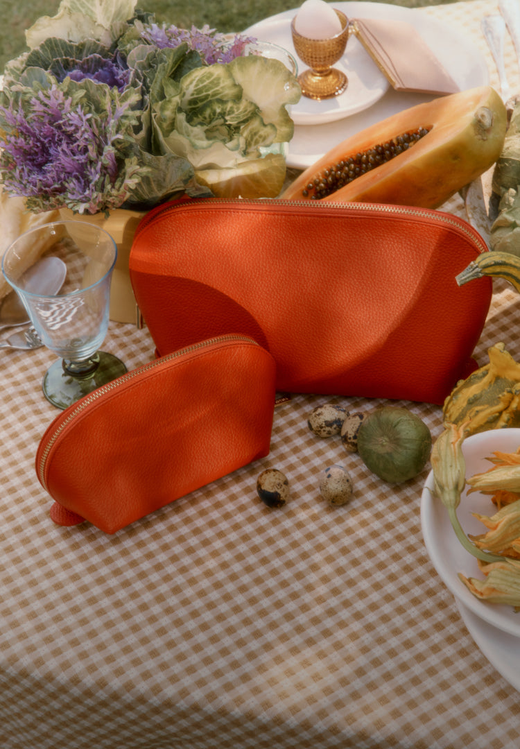Right: Red/orange leather pouched next to produce and greenery. 