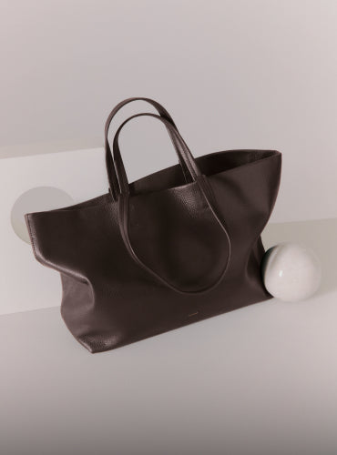 Large tote bag with handles next to a round object.