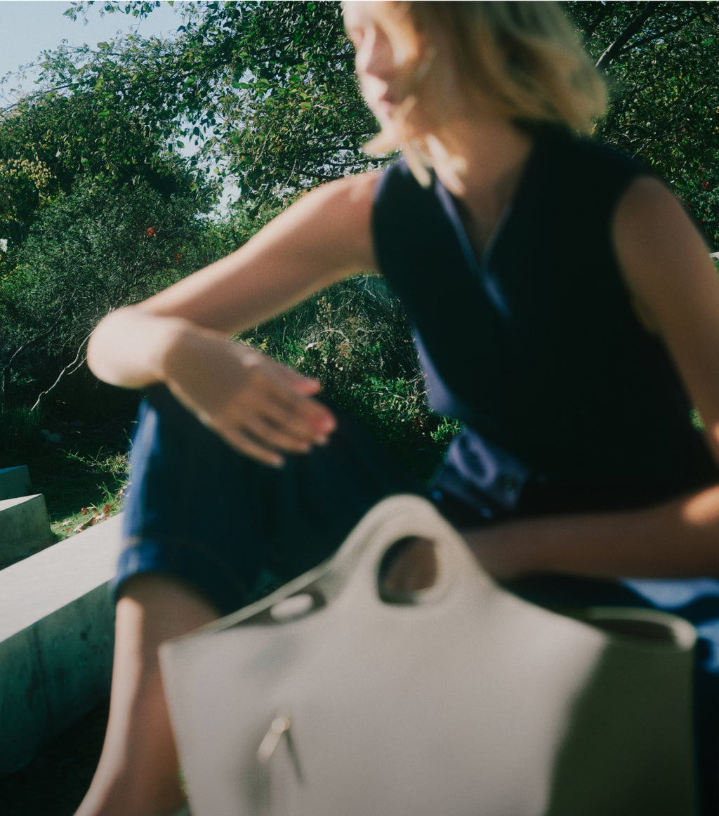 Person sitting outdoors holding a large bag.