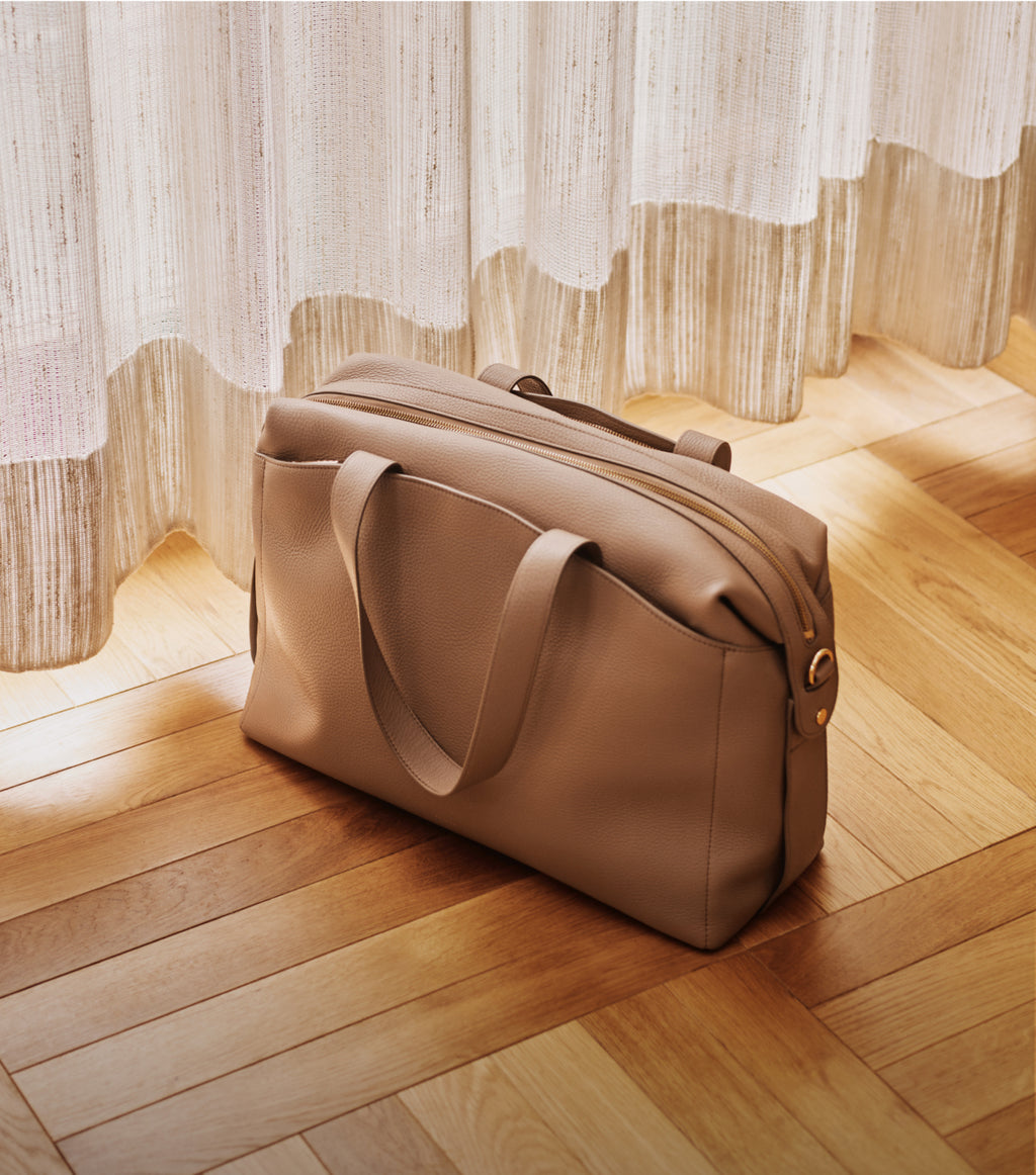 Travel bag on wooden floor near curtains