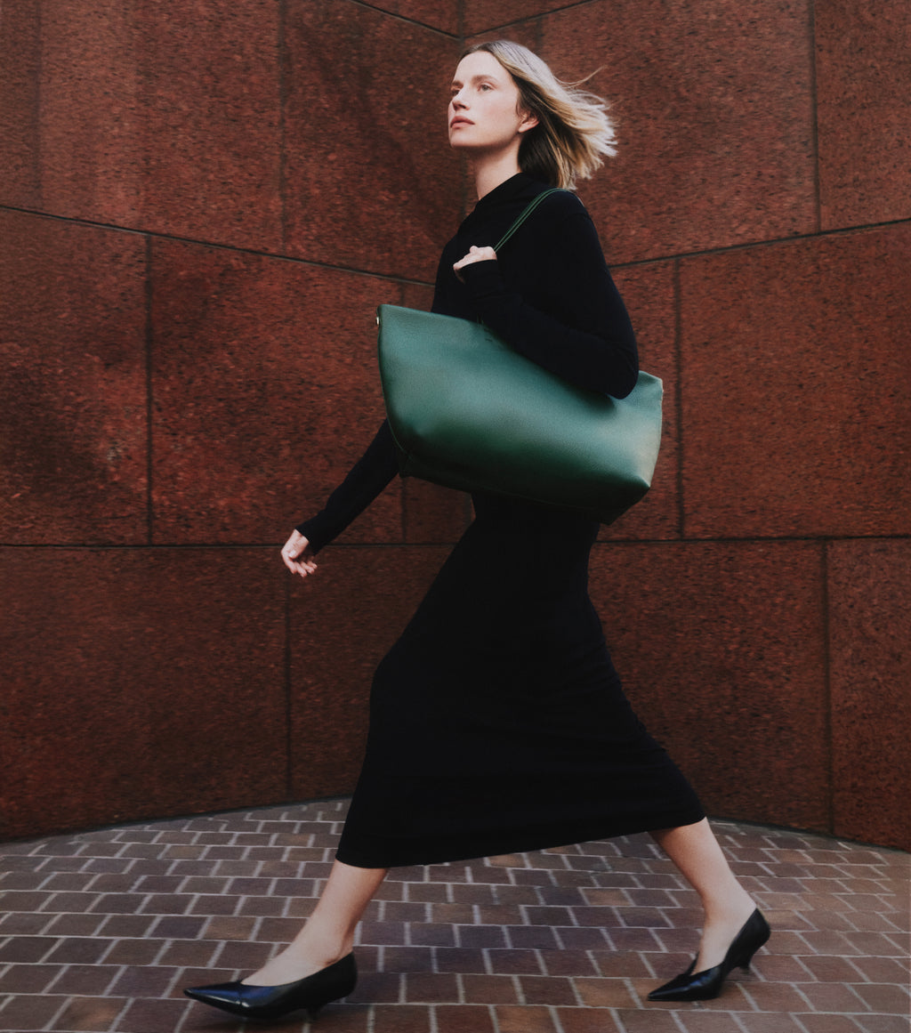 Person walking with a large bag on a brick path.