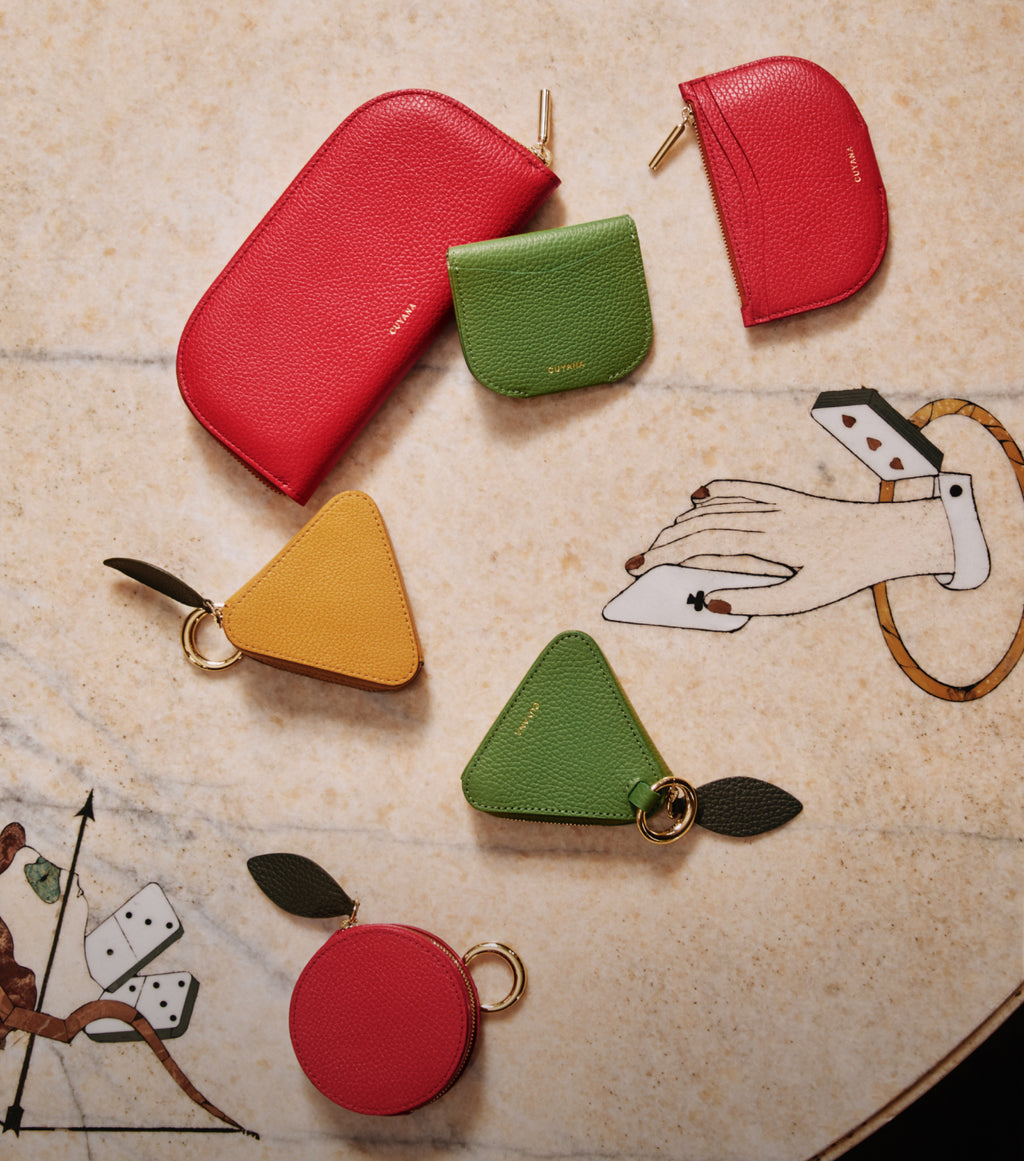 Various shaped wallets and pouches on a table with a hand illustration.