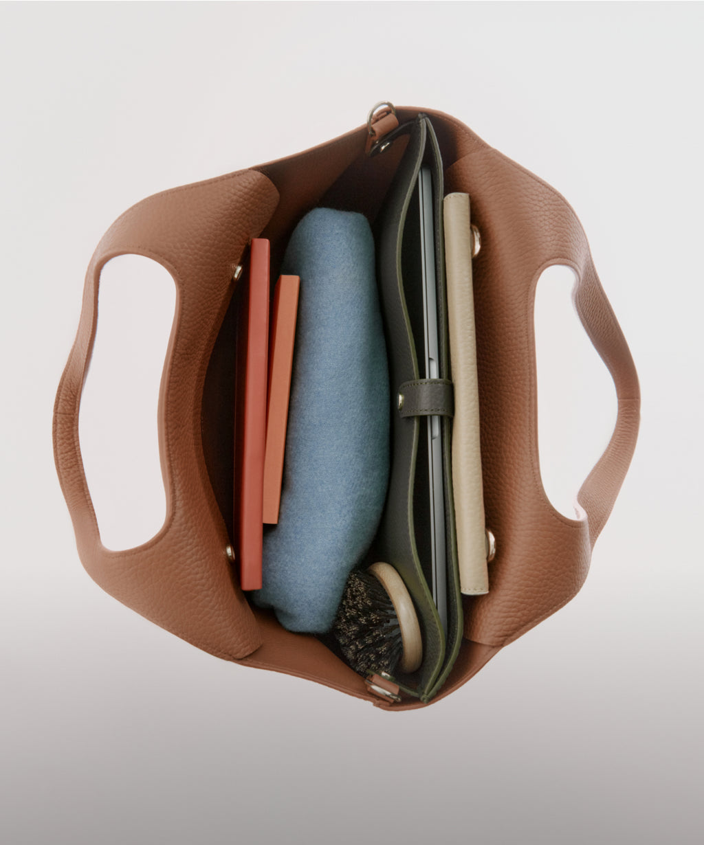 Linked Image: Directs to 9-5 Systems. A shop page with information on Cuyana product Systems. (cuyana.com/pages/your-9-5-system-system-tote). Image Description: Showing the Interior of the Cuyana System Tote in color Caramel. Inserted inside the tote are notebooks, a sweater, a hairbrush, a laptop in a laptop sleeve and a wallet.