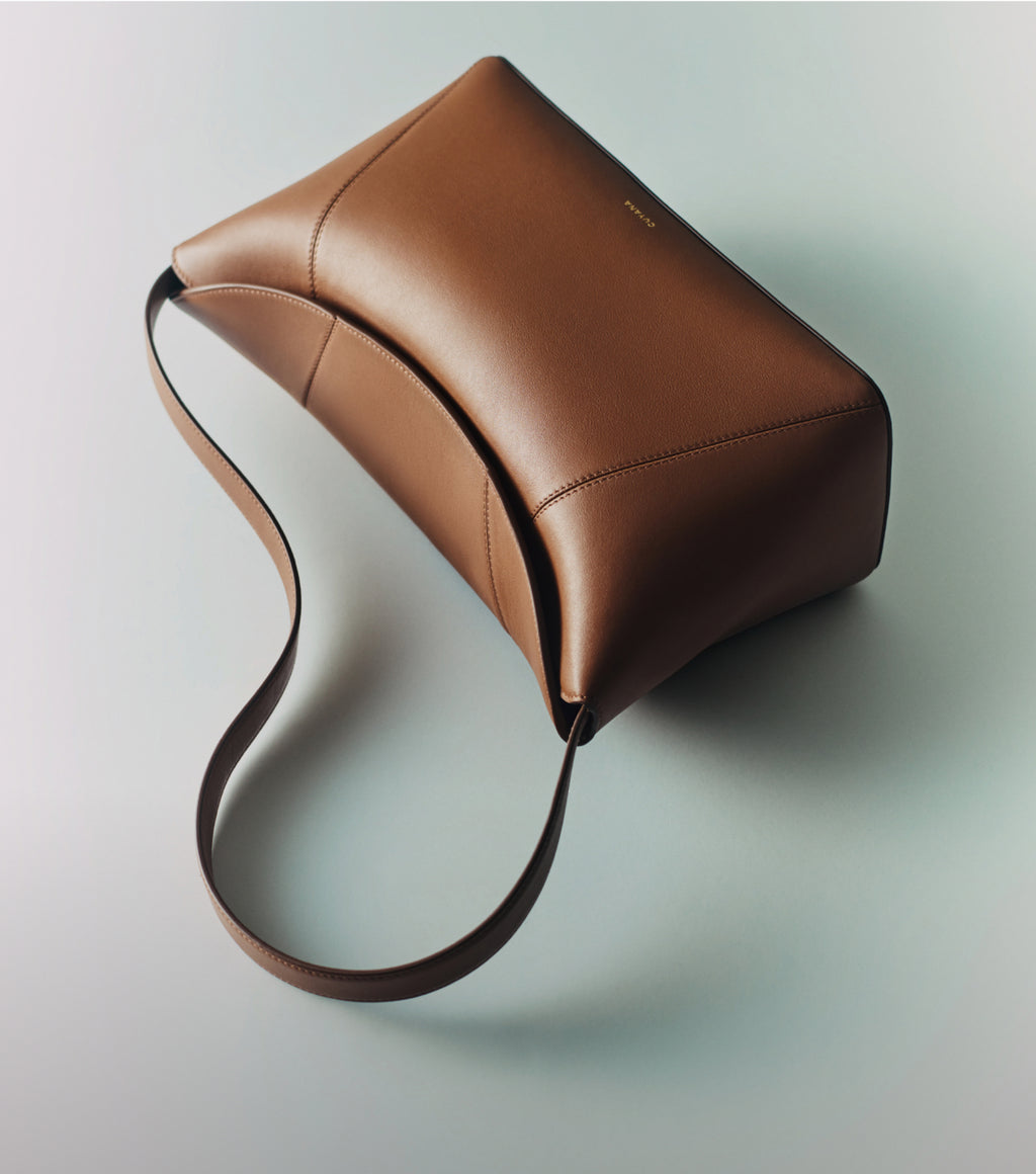 Rectangular leather bag with a long strap on a flat surface