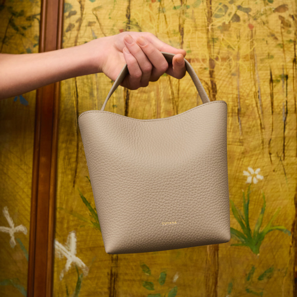 Person holding a small handbag in front of a patterned background