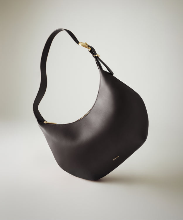 A hobo bag with a curved shape and wide strap displayed on a plain background.