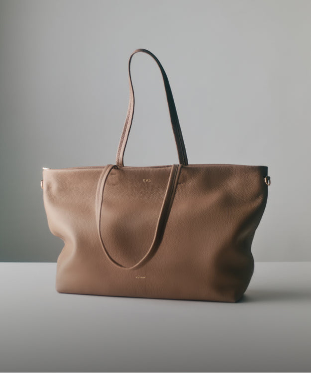 Large tote bag with thin shoulder straps on a flat surface.