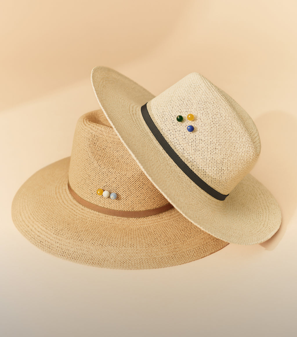 Two straw hats with small round embellishments.