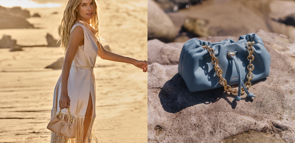 Person on beach holding bag, blue handbag with chain on rocks.