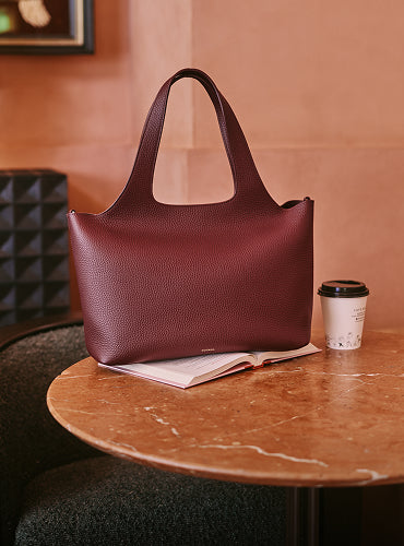 Handbag on a table with book and coffee cup nearby