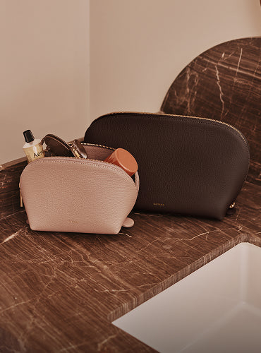 Two toiletry bags on a countertop, filled with various items.