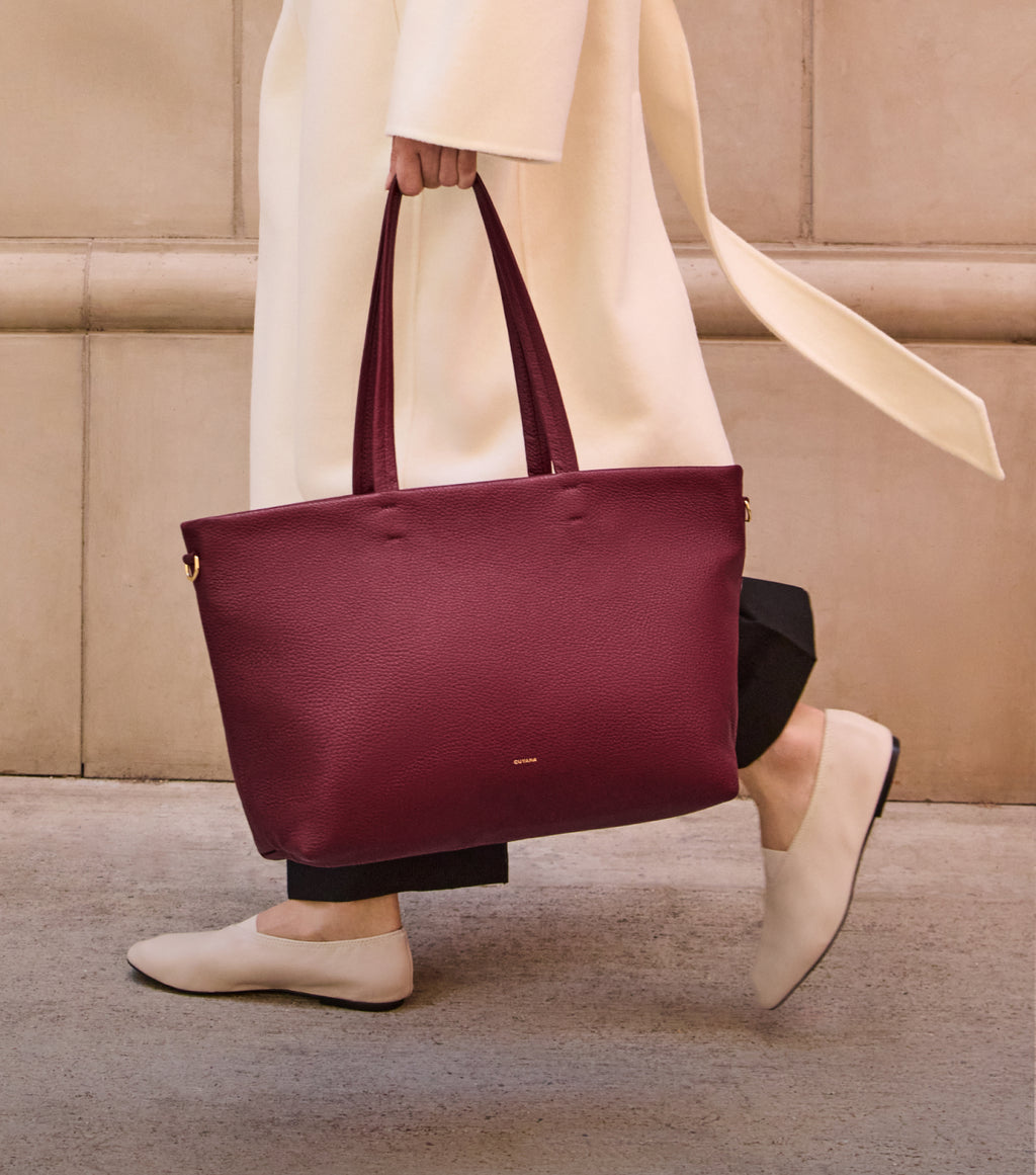 Person walking with a handbag wearing long coat and flats