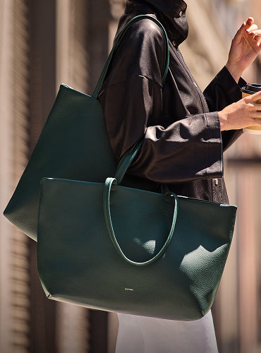 Person holding a large handbag and a coffee cup.