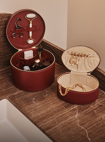 Two round organizers for cosmetics and jewelry on a marble surface.