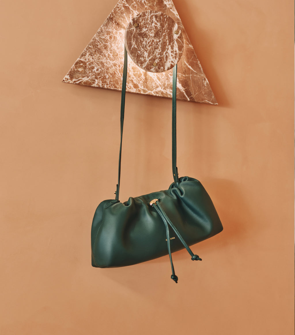 Shoulder bag hanging on a triangular marble shelf.