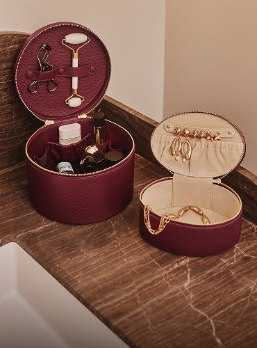 Two round organizers with cosmetics and jewelry near a sink.