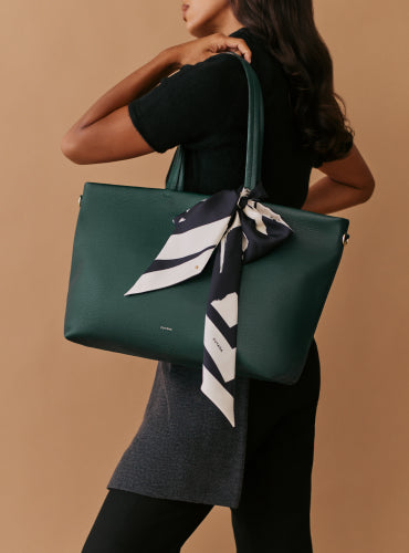 Person holding a handbag with a scarf attached.